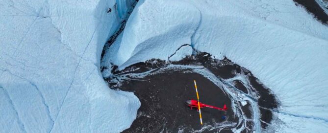 aerial view of ice climbers and red helicopter on glacier