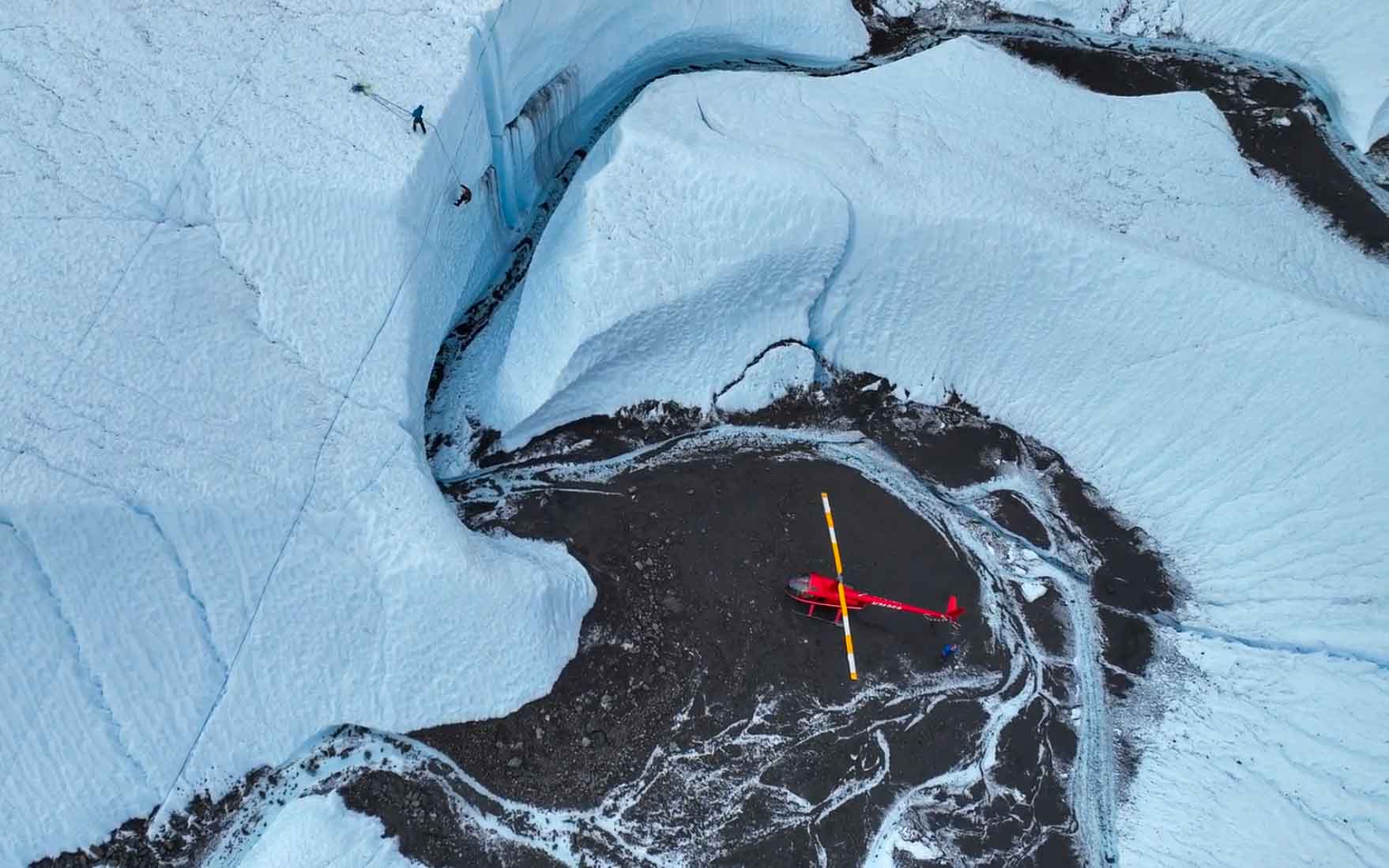 aerial view of ice climbers and red helicopter on glacier
