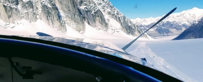 view of snowy mountain tops from inside of helicopter