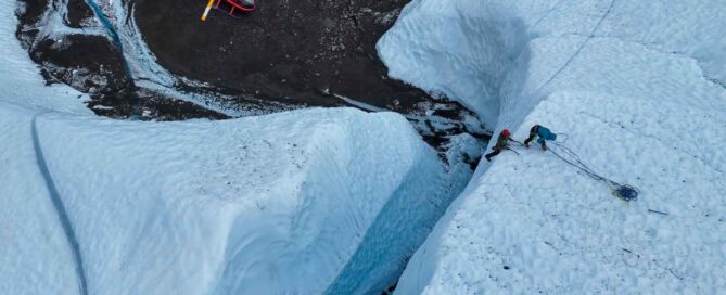aerial view of two climbers climbing above helicopter