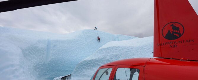 people ice climbing in distance with helicopter in foreground