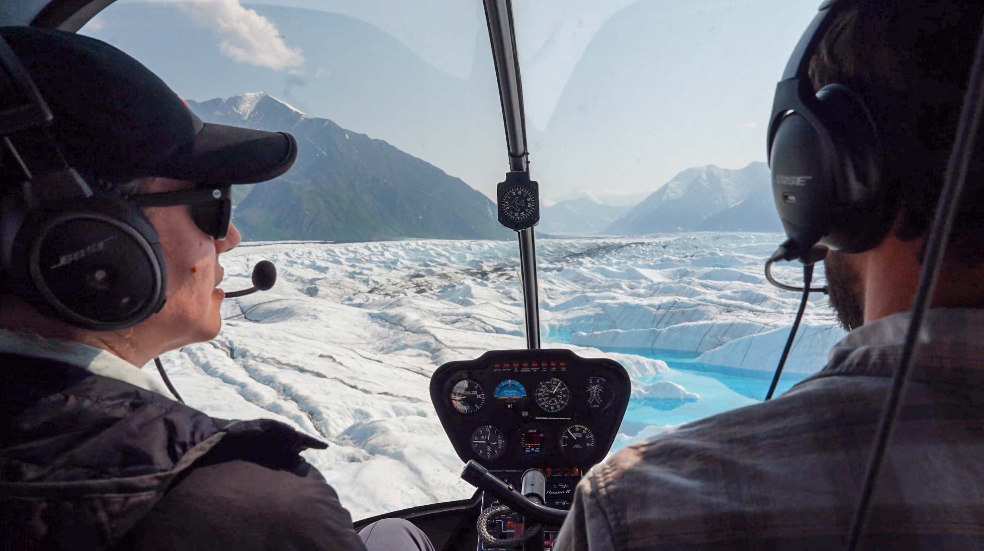 pilot and passenger looking across glacier scenery from inside helicopter