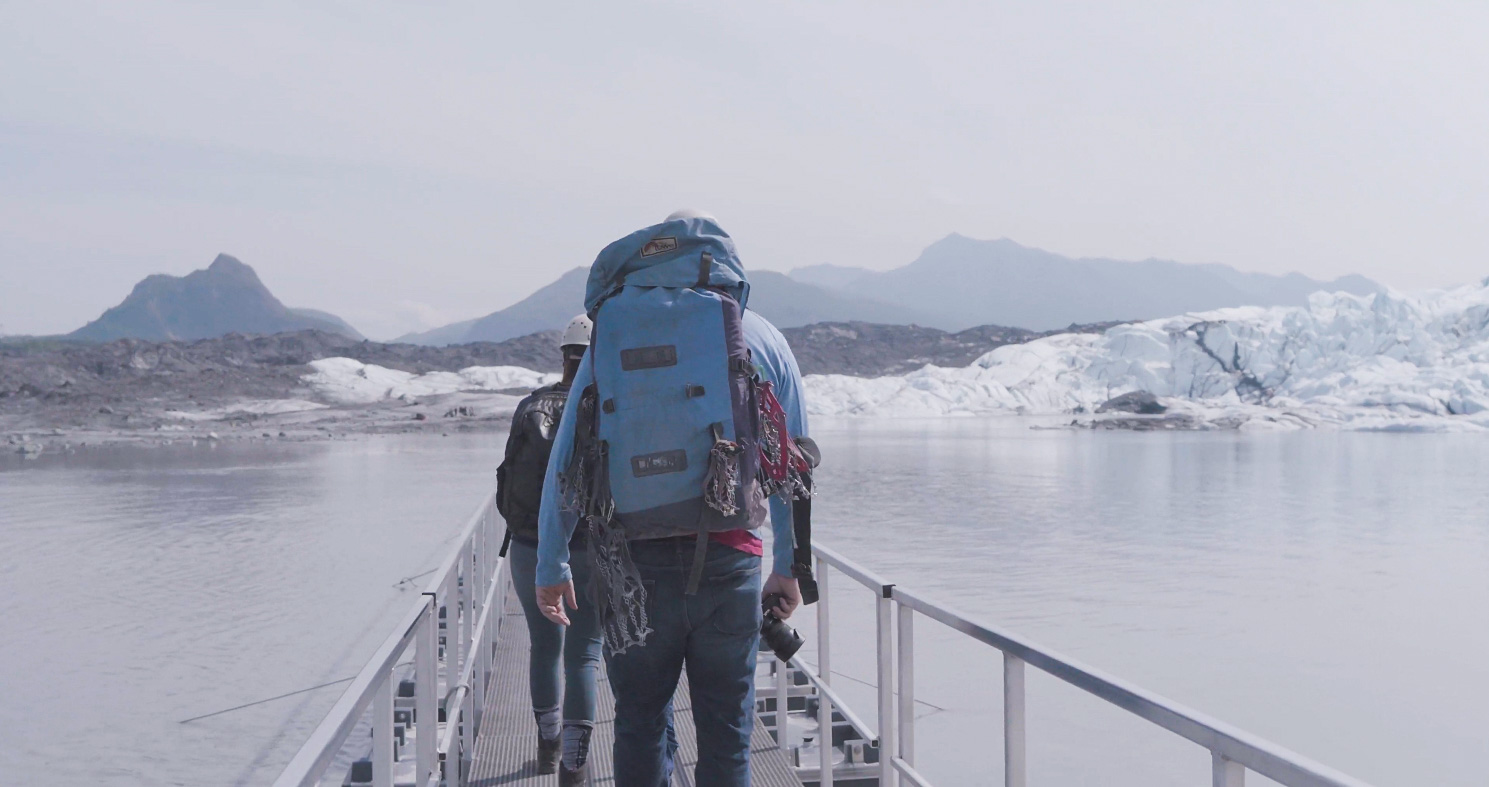 people walking across bridge to solid glacier ice
