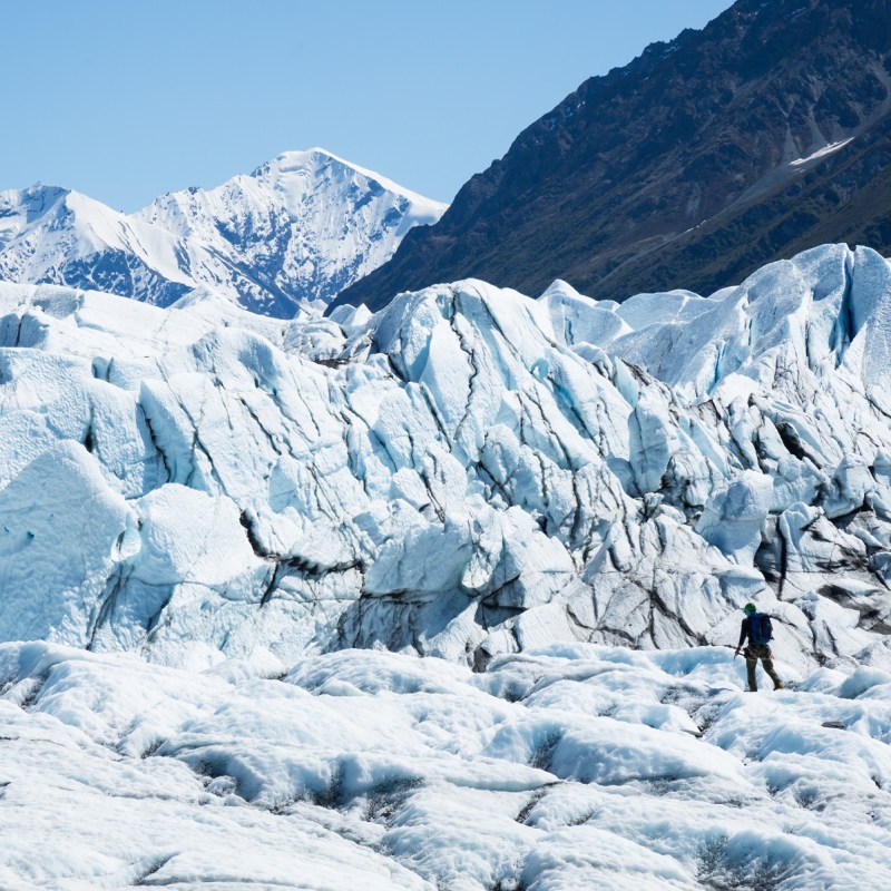 Person walking to glacier ice fall