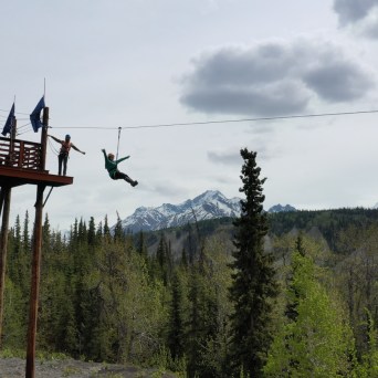 person with arms wide open going down zipline