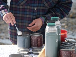 person wearing flannel stirring coffee with spoon