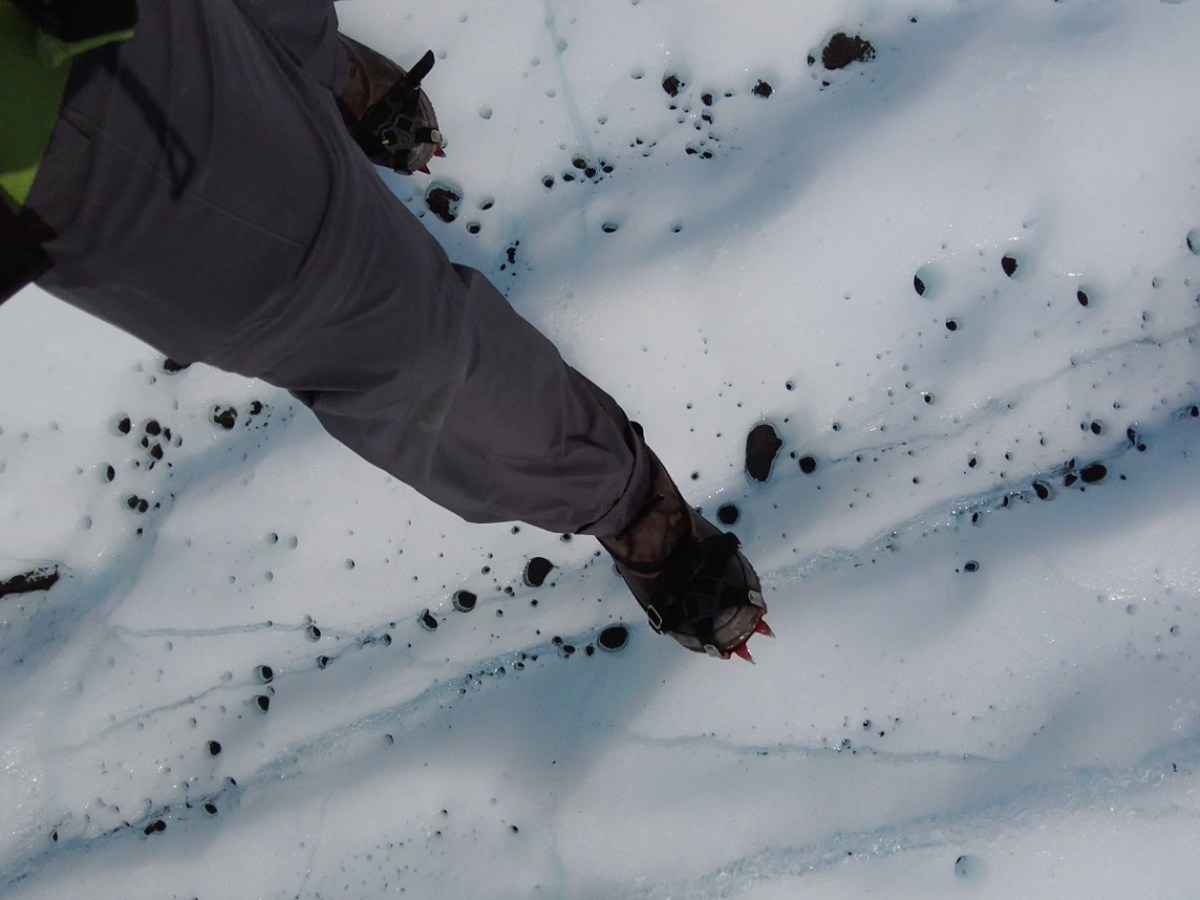 person steps on white ice of glacier in Alaska