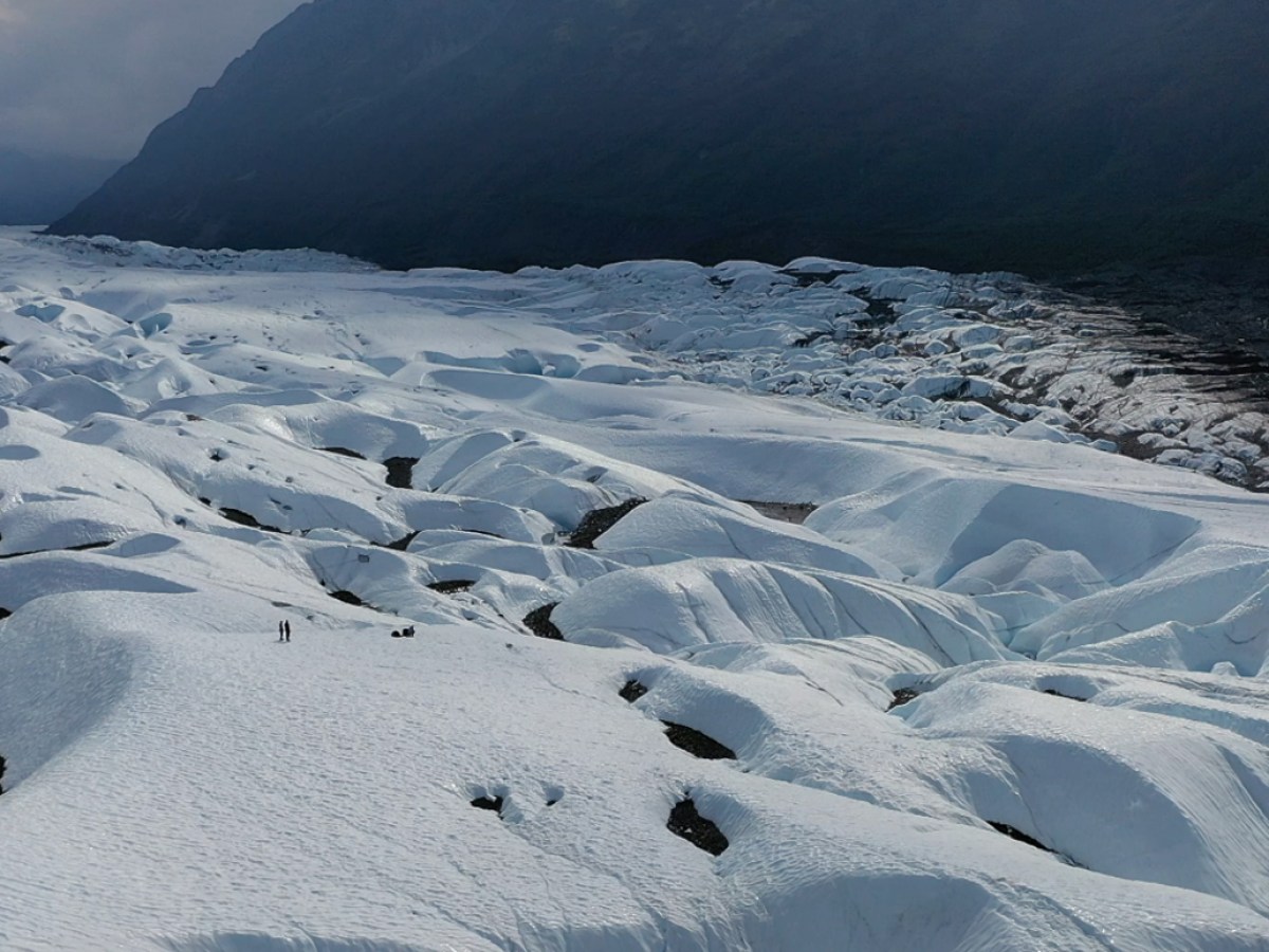 people walk over remote area of glacier