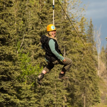woman with yellow helmet looking back on zipline