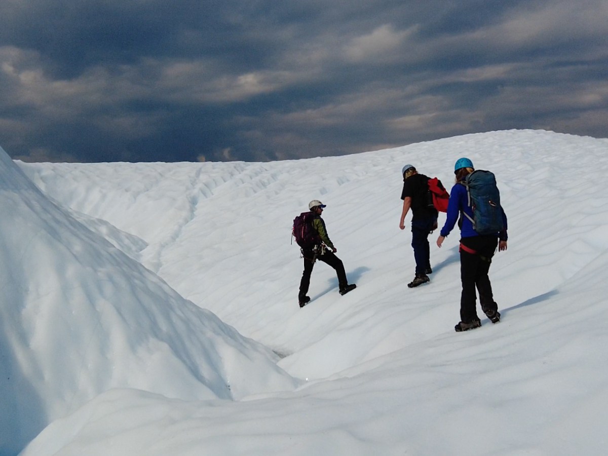 people walking sideways along white ice with crampons on
