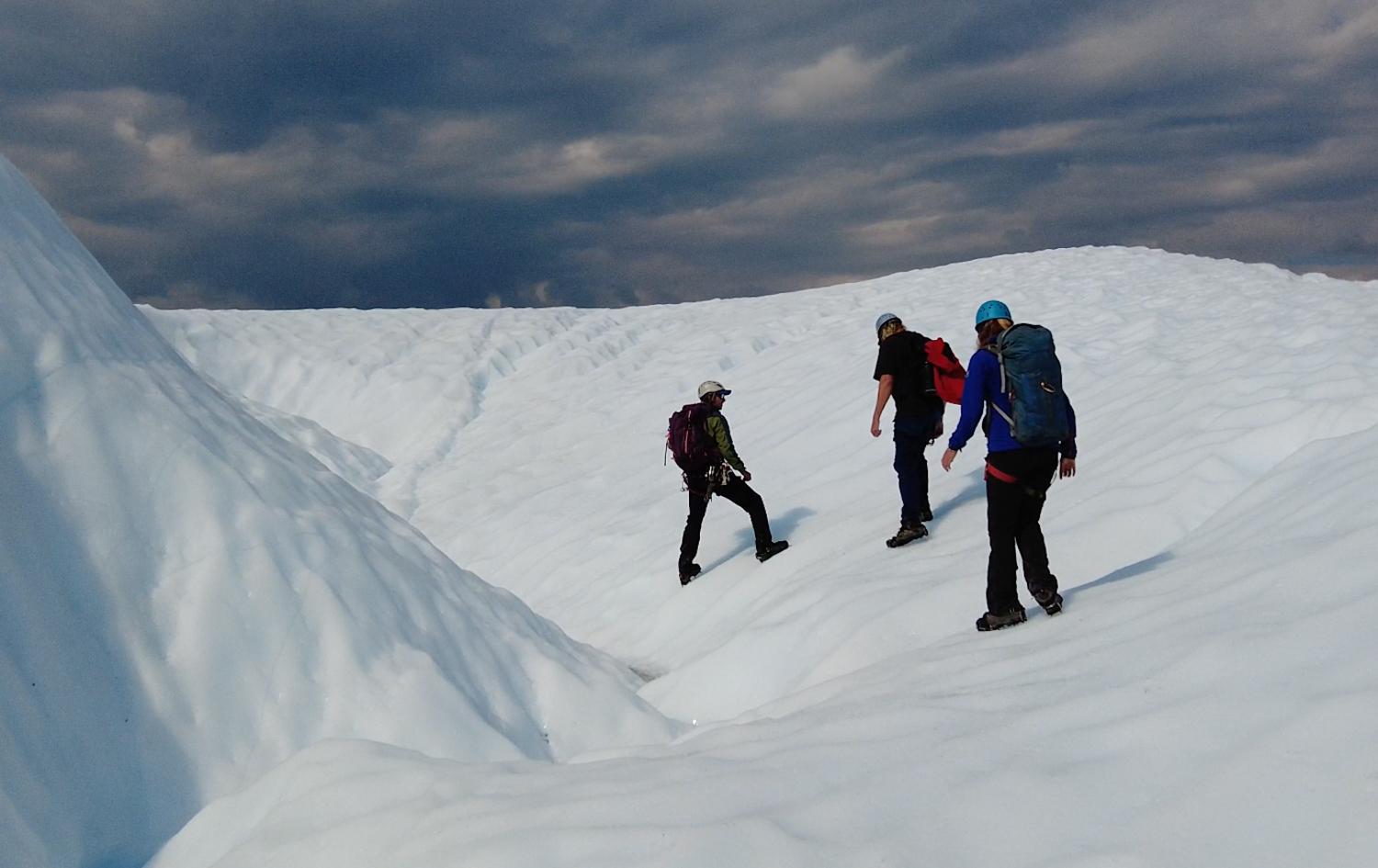 people side stepping sloped white ice people walking sideways along white ice with crampons on