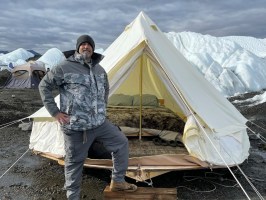 Man posing in front of canvas tent on Matanuska Glacier