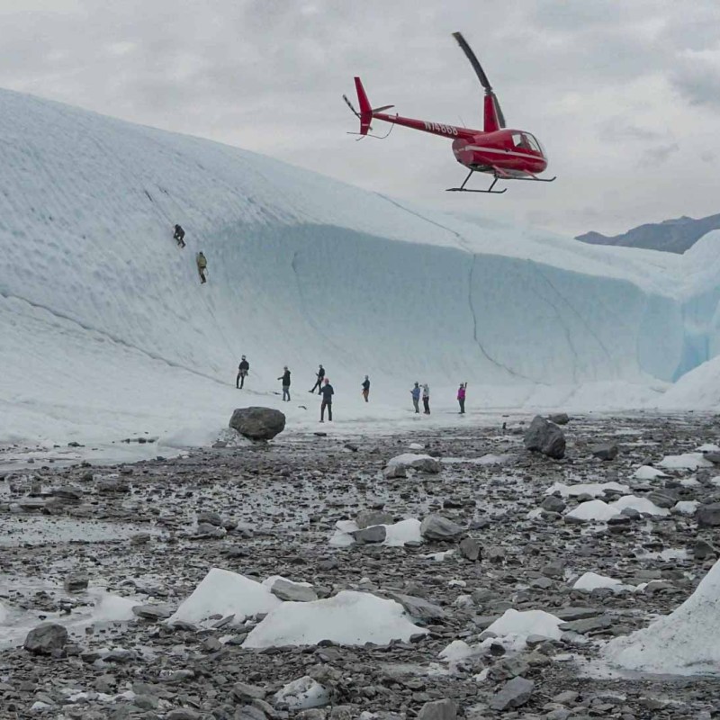 Helicopter taking off from group ice climbing on glacier