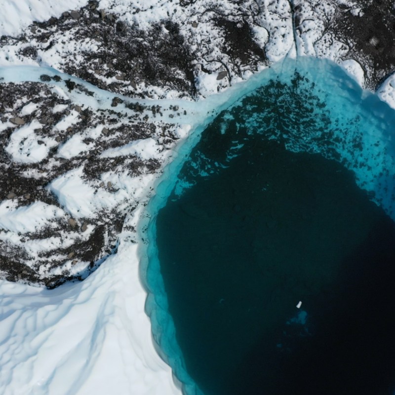 blue pool on glacier with rocks and ice