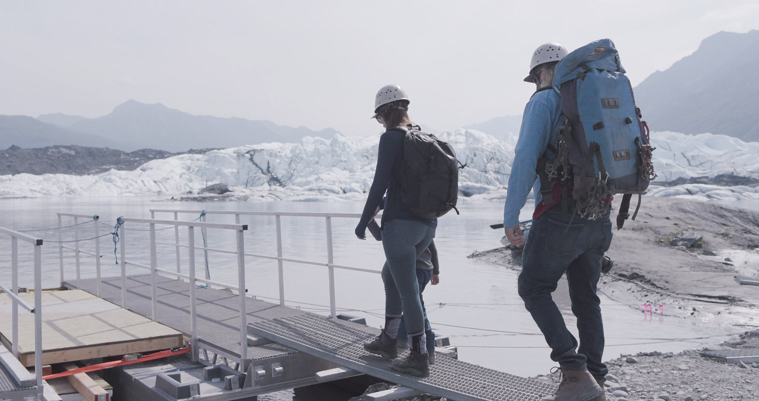 Glacier meltwater and people family walking on platform next to glacier meltwater and ice